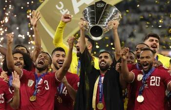Qatar's forward #10 Hassan Al-Haydos lifts the Qatar 2023 AFC Asian Cup trophy as his team celebrates during the podium ceremony after the final football match between Jordan and Qatar at the Lusail Stadium in Lusail, north of Doha on February 10, 2024. (Photo by Giuseppe CACACE / AFP)