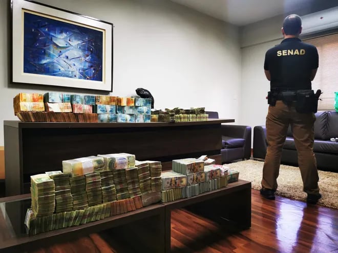 Un agente de la Senad custodia el dinero incautado el jueves en una casa de cambios en Asunción.
