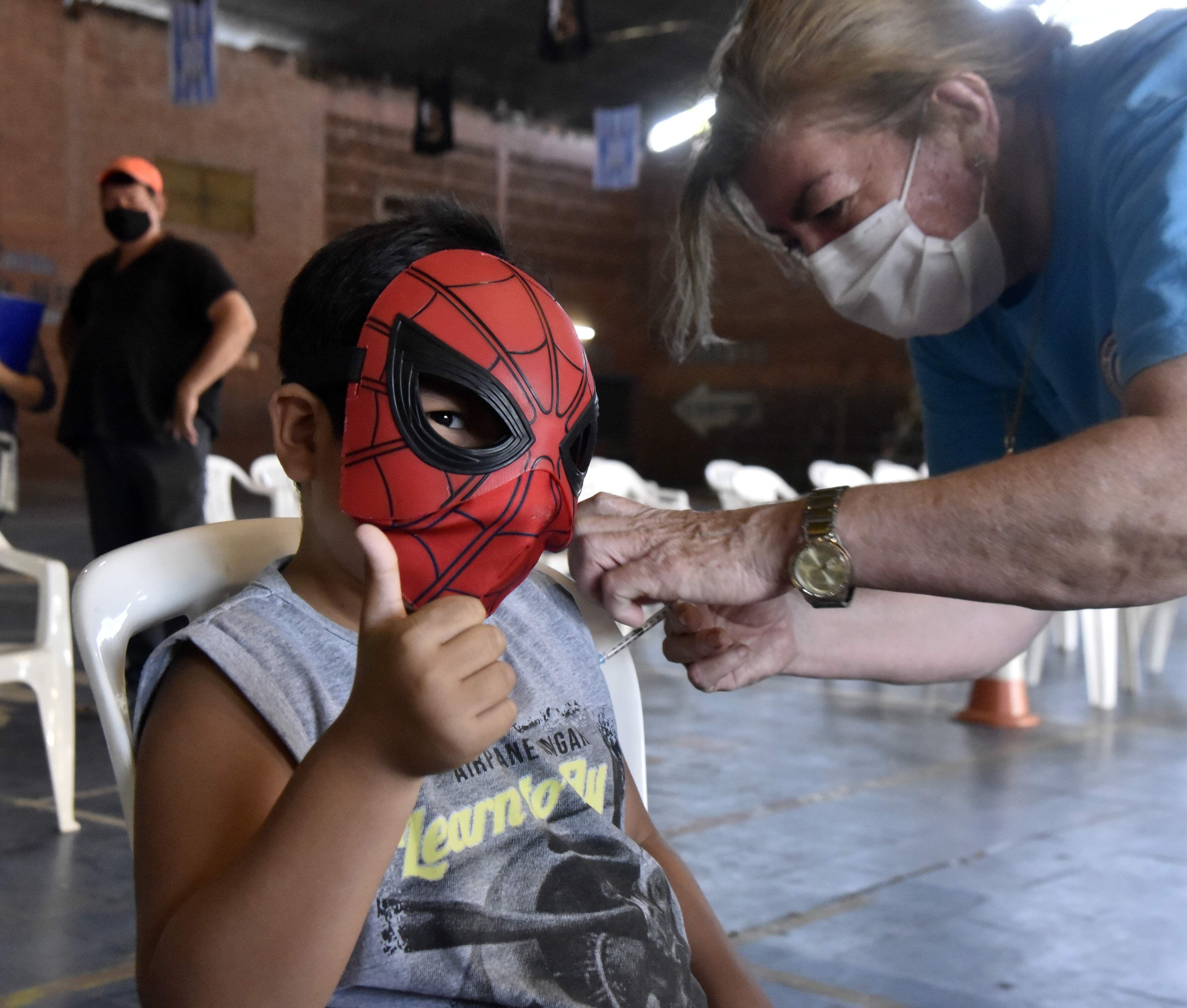 Un pequeño enmascarado de Spiderman muestra la emoción de recibir la primera dosis en el club Fomento de barrio Obrero.