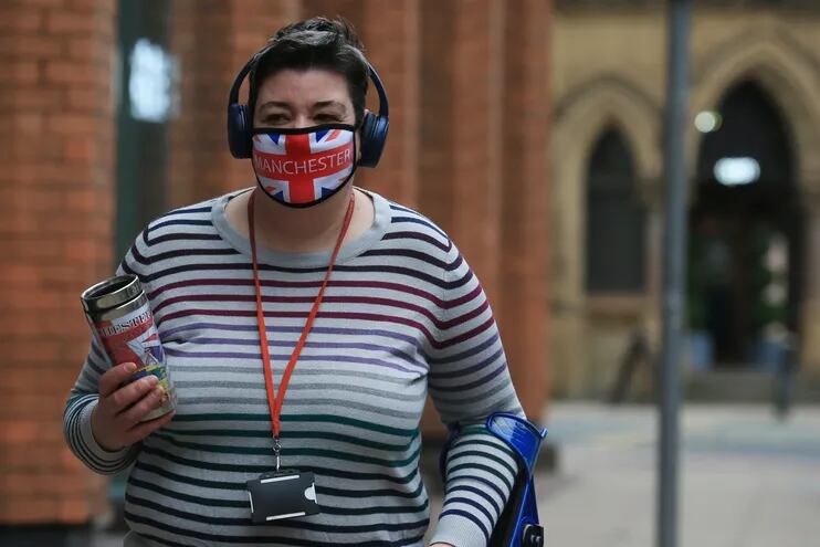 Una mujer con mascarilla camina por el centro de Manchester, Inglaterra.