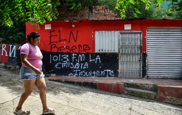 Una mujer pasa frente a una casa con un grafiti del grupo guerrillero ELN.