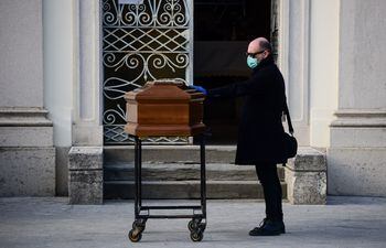 Un hombre toca el ataúd de su madre durante un servicio funerario en el cementerio cerrado de Seriate, cerca de Bérgamo, Lombardía.