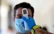 Un trabajador sanitario le toma la temperatura a un hombre en un centro de pruebas temporal para el nuevo coronavirus en Madrid.