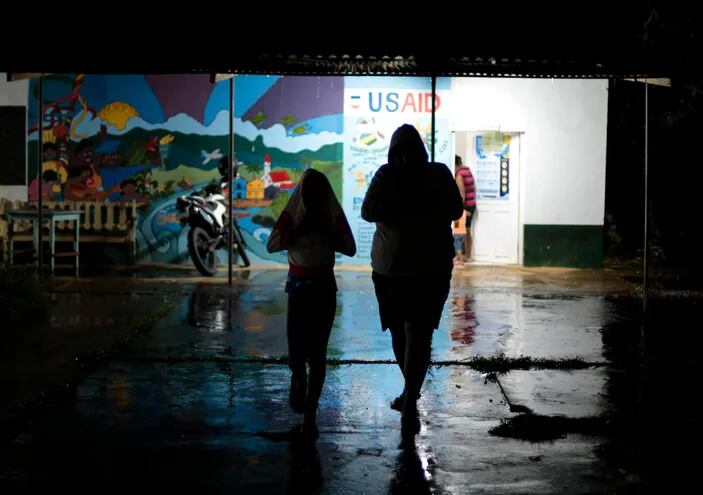 Una mujer y un niño caminan en un refugio temporal antes de la llegada de la tormenta tropical Bonnie en Bluefields, Nicaragua.