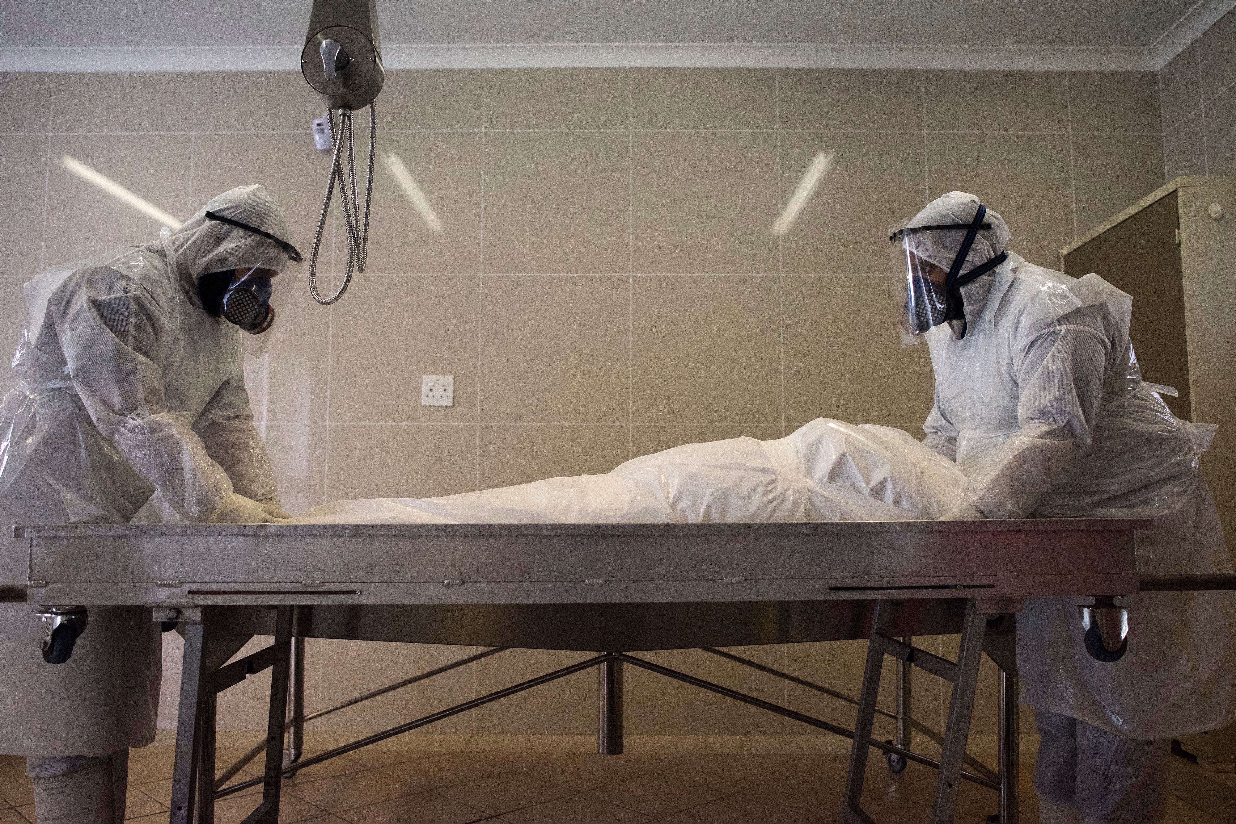Funcionarios de una funeraria musulmana preparan el cuerpo de un hombre fallecido por COVID-19 para su entierro en la mezquita Ghietmatiel Islamia en Ciudad del Cabo, Sudáfrica.