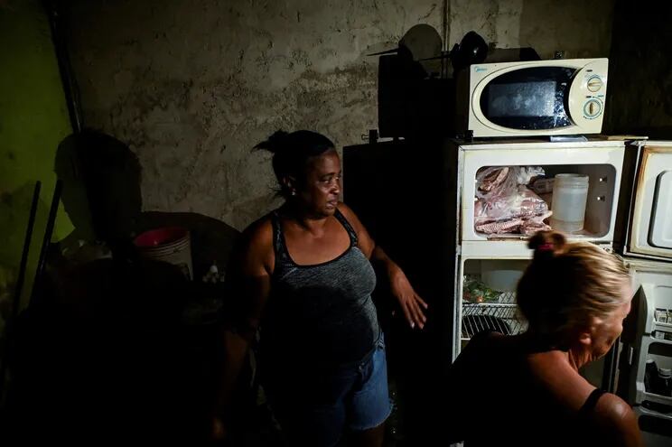 Women are seen in their house without electricity in the aftermath of Hurricane Ian in Havana on September 29, 2022. - The National Electric System (SEN) collapsed on Tuesday, leaving the island blacked out due to the damage caused by the powerful hurricane Ian, which caused the death of three people and severe damage in the western part of the country. (Photo by YAMIL LAGE / AFP)