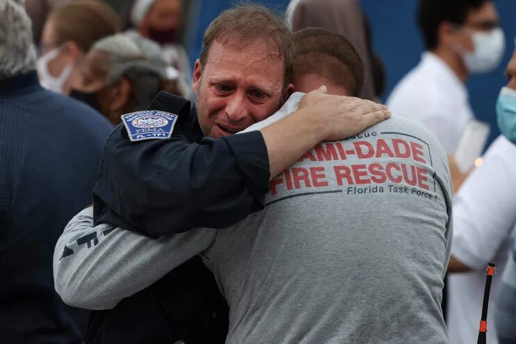 Rescatistas del Miami Dade Fire Rescue se abrazan durante un minuto de silencio cerca del memorial levantado para las víctimas del colapso del edificio Champlain Towers South.