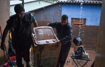 Everton Lemes (i) y su cuñado Brayon Jost cargan una heladera afectada por la inundación en el municipio de Río Pardo, estado de Rio Grande do Sul (Brasil).