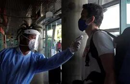 Un empleado le toma la temperatura a un pasajero a su ingreso al aeropuerto internacional Rafael Núñez de Cartagena (Colombia).