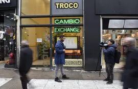 Transeúntes caminan afuera de una casa de cambio, en Buenos Aires (Argentina). (EFE)