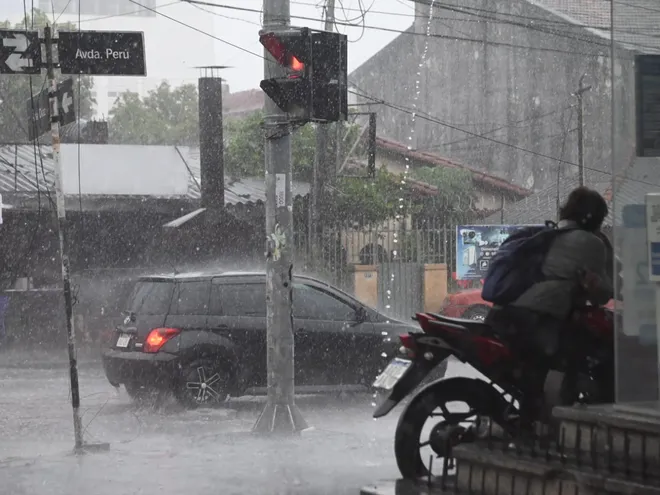 Conductores de motos y automóviles bajo la lluvia en Asunción.
