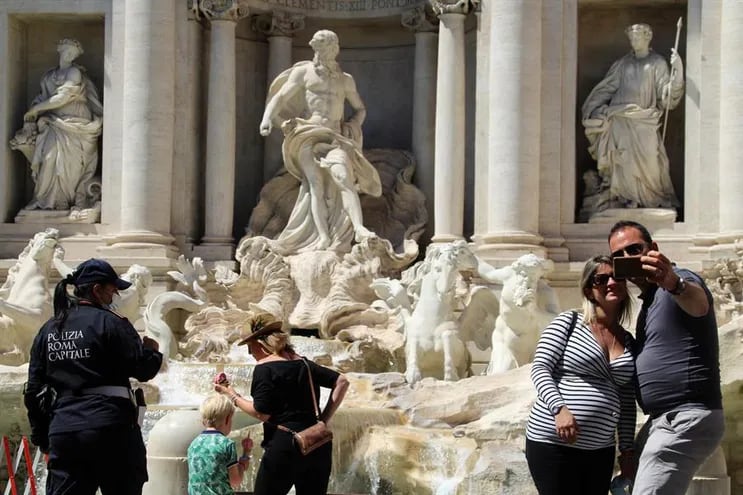 Los monumentos italianos, vacíos durante meses, vuelven a llenarse poco a poco de turistas gracias a la reducción de las restricciones y la mejora de los datos epidemiológicos. En la imagen, varios turistas visitan la Fontana de Trevi, en Roma.