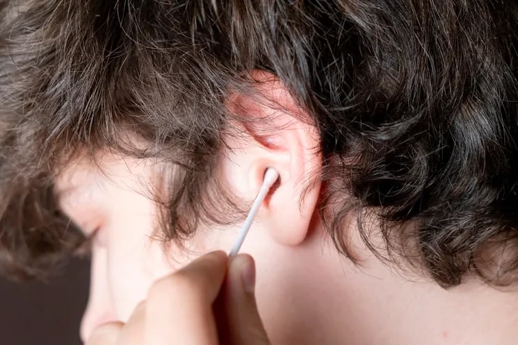 Un joven se limpia la oreja con un cotonete