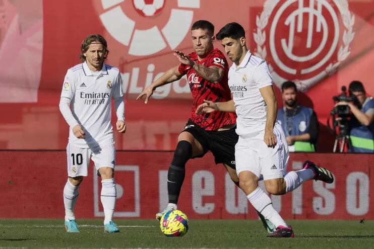 El defensa del Real Mallorca Nastsic (c) disputa el balón ante el delantero del Real Madrid Marco Asensio (i) durante el Partido de La Liga que juegan el Mallorca y el Real Madrid en el estadio de Son Moix.