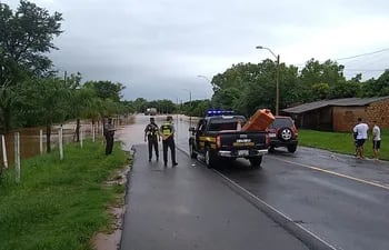 Agente policial, de la Patrulla Caminera y Bomberos Voluntarios trabajan para evitar que se cruce la calzada del arroyo Yaguarón.