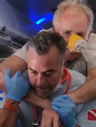 Martín Britos Bray, médico paraguayo, asistiendo a otro pasajero en pleno vuelo desde Honduras a EE.UU.