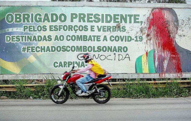 Un cartel con la imagen de Jair Bolsonaro fue manchada con pintura roja en una protesta. (AFP).