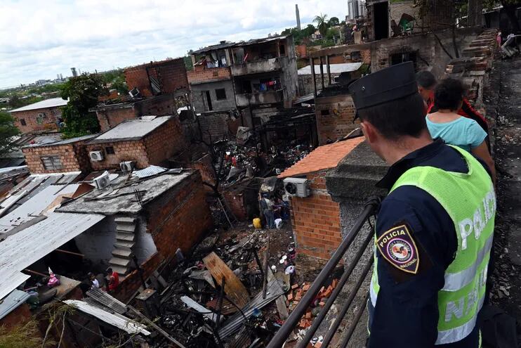 Un agente de la Policía Nacional y vecinos observan la zona de la Chacarita afectada por el incendio del pasado viernes.