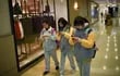 Tres niñas caminan por los pasillos de un shopping mirando las pantallas de sus teléfonos celulares, en Pekín, China.
