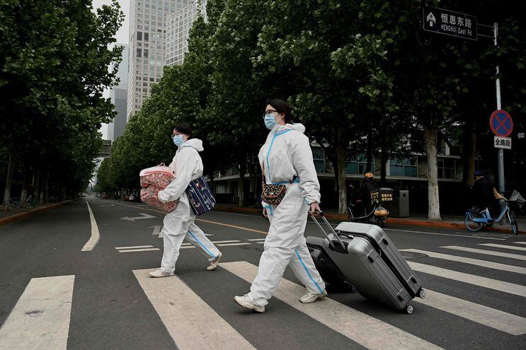 Personas visten equipos de protección personal en una calle de Pekín, China.  (AFP)