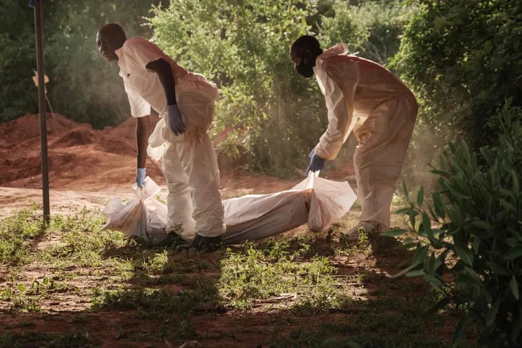 Trabajadores llevan una bolsa para cadáveres a la morgue después de exhumar los cuerpos en la fosa común en Shakahola, en las afueras de la ciudad costera de Malindi. El número de muertos en una investigación vinculada a un culto keniano que practicaba la hambruna aumentó a 201.