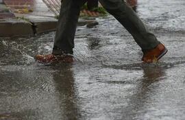 Imagen de archivo de una persona cruzando la calle en un día lluvioso.
