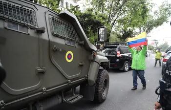 Un hombre exhibe una bandera mientras pasa un vehículo blindado donde es trasladado el exvicepresidente ecuatoriano Jorge Glas, este sábado en Quito (Ecuador).