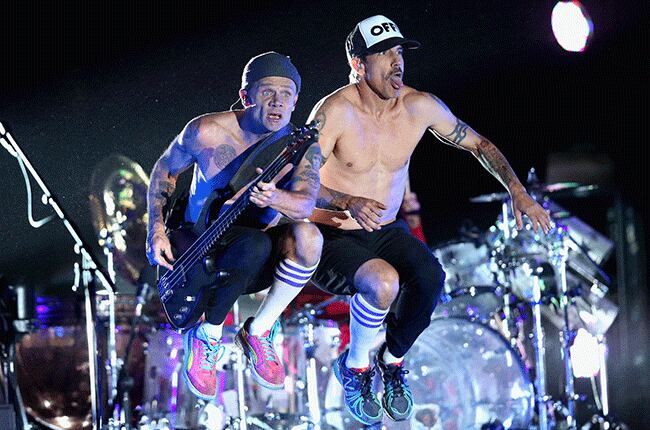 Flea y Anthony Kiedis saltan en el escenario durante un show de los Red Hot Chili Peppers.