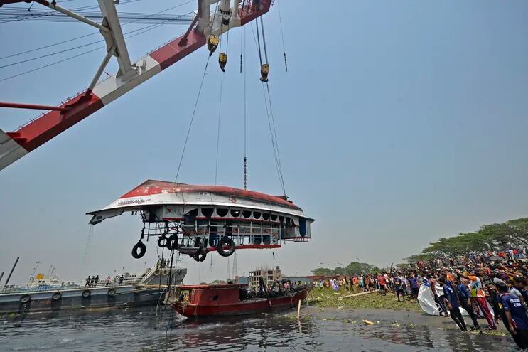 Los pobladores y familiares se reúnen después de que las autoridades recuperaran el bote volcado en el río Shitalakshya, en Narayanganj, el 5 de abril de 2021.