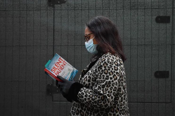 Una mujer lee un libro mientras espera en fila en un centro de provisión de vacunas contra la covid -19 en Londres.