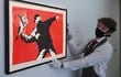 Un empleado de la galería posa junto a una obra de arte titulada 'El amor está en el aire', del artista británico Banksy, mientras Christie's se prepara para reabrir al público.