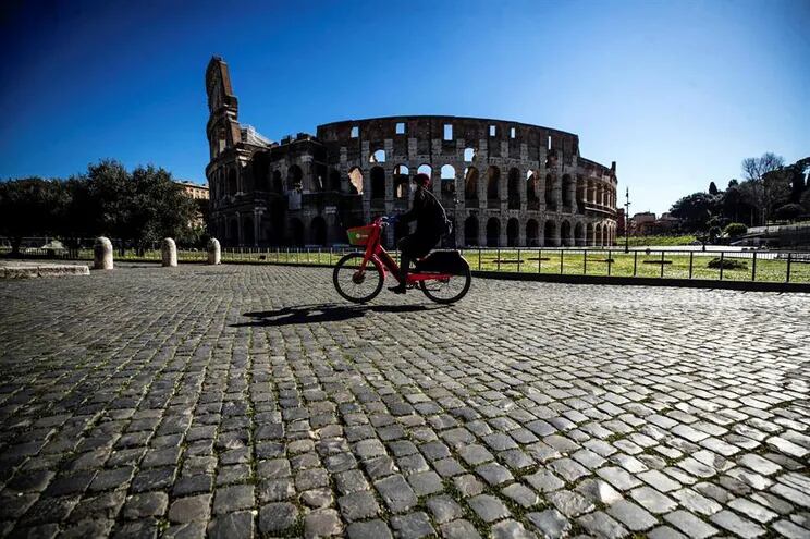 Una persona pasea en bicicleta ante el Coliseo romano.