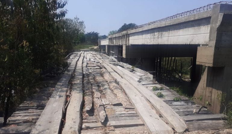 La precaria pasarela de madera está por colapsar, según pobladores. Al lado,  la estructura de hormigón armado   abandonada.