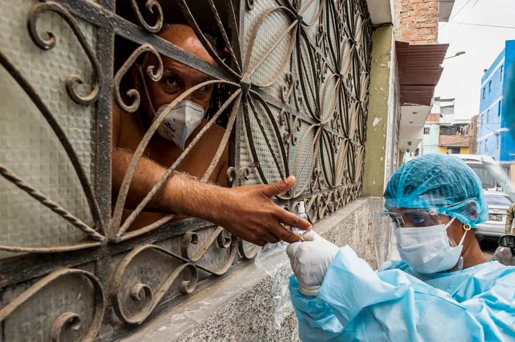 Un trabajador de la salud toma una muestra para prueba de covid-19 a una persona en su domicilio en Lima, Perú.