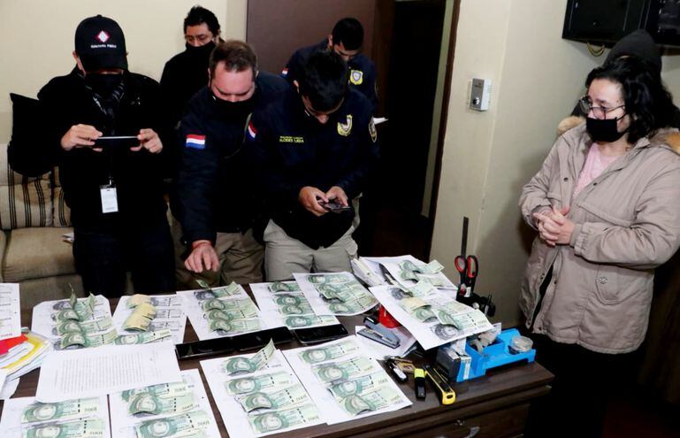 Ante la atenta mirada de la fiscala Sonia Pereira, agentes policiales proceden a cotejar los billetes incautados, con las fotocopias previamente realizadas por disposición fiscal. Fue ayer, en Luque.