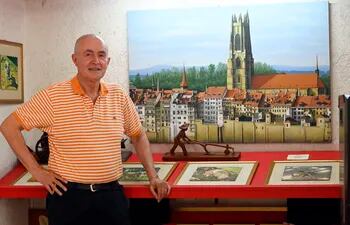 Claude Hurard, propietario del Aparthotel Maison Suisse, frente a una pintura de su ciudad natal.