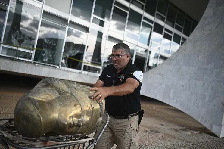 Un agente de la policía federal levanta la cabeza de una estatua tras revisar la destrucción en la sede del Tribunal Supremo después de las protestas del  domingo 8 de enero en Brasilia (Brasil).