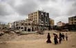 Los palestinos pasan junto a edificios dañados en Khan Yunis el 8 de abril de 2024 después de que Israel retirara sus fuerzas terrestres del sur de la Franja de Gaza, seis meses después de la devastadora guerra provocada por los ataques del 7 de octubre.