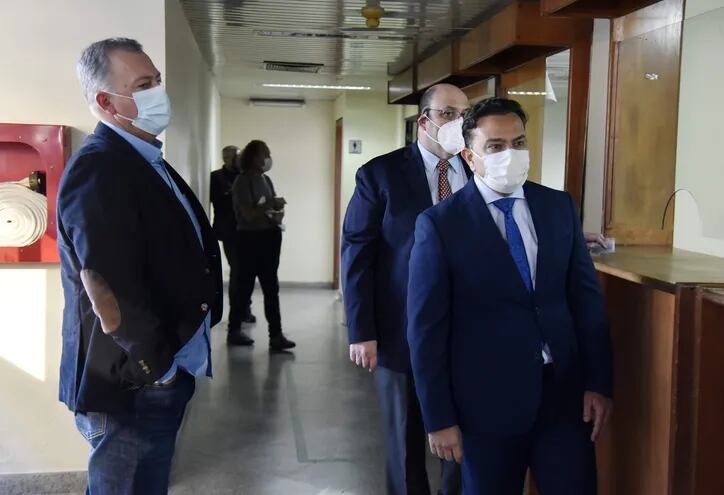 Roque Silveira (i) espera el momento de firmar el acta, ante la secretaría del juzgado de garantías. Lo acompañan sus abogados Arturo Daniel y Andrés Casati.