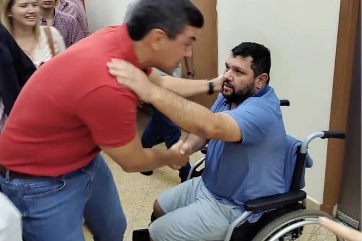 Santiago Peña (remera colorada), abrazando a Oswaldo Eustáquio (en silla de ruedas). en sede del Partido Colorado en Asunción. (gentileza).