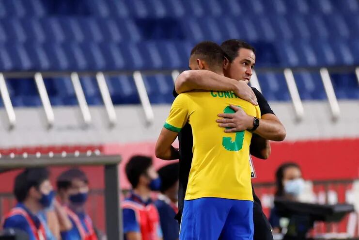 El delantero brasileño Matheus Cunha (i) se abraza con su entrenador André Jardine durante el encuentro de cuartos de final entre las selecciones de Brasil y Egipto, durante los Juegos Olímpicos 2020, este sábado en el Estadio de Kashima (Japón).
