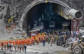 El personal de la Fuerza Nacional de Respuesta a Desastres (NDRF) junto con otros operativos de rescate se reúnen cerca de la cara del túnel Silkyara en construcción colapsado en el distrito de Uttarkashi del estado indio de Uttarakhand, el 28 de noviembre de 2023. Los equipos de rescate indios que excavan a mano están abriéndose paso para llegar a 41 hombres atrapados en un túnel de carretera derrumbado.