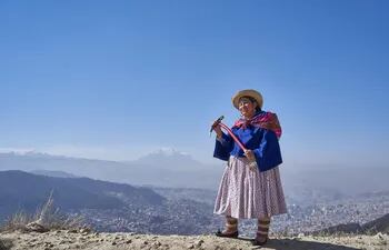 Teodora Magueno, escaladora y guía de montaña, posa con la cima del Illimani y la ciudad de La Paz de fondo.