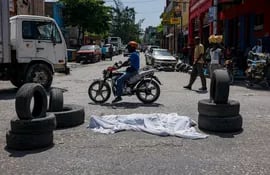 Un cadáver cubierto con una sábana yace en medio de una calle en el centro de Puerto Príncipe, capital de Haití.