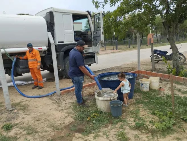 Desde un camión cisterna descargan el agua cruda tomada del río Paraguay para las familias de Carmelo Peralta, donde no logran solucionar la falta de sistema de suministro de agua potable.