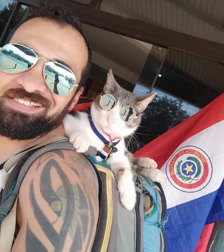 Jhon Galvis y la gata Bella, conocida como el Gato mochilero, en una foto que publicaron el 14 de agosto para celebrar el Día de la Bandera paraguaya.