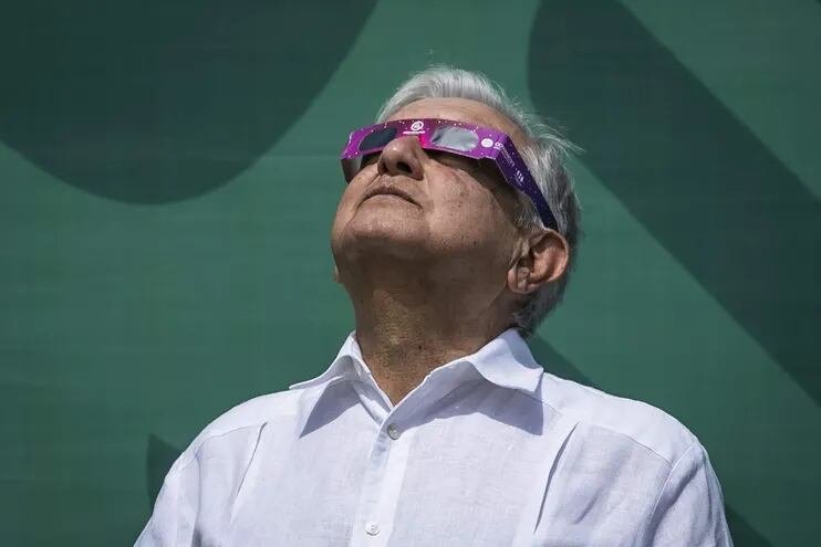 El presidente mexicano, Andrés Manuel López Obrador, usa gafas de sol especiales mientras observa un eclipse solar momentos antes de su totalidad, en Mazatlán, estado de Sinaloa, México,