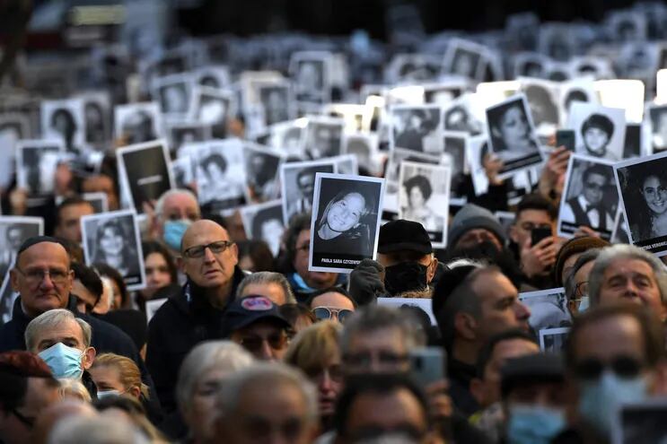 Relatives of victims of a bomb attack to the Jewish community centre of the Mutual Israelite Association of Argentina (AMIA) that killed 85 people and injured 300, hold photos during its 28th anniversary, in Buenos Aires, Argentina, on July 18, 2022. (Photo by Luis ROBAYO / AFP)
