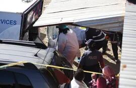 Efectivos y forenses de la policía sudafricana transporta uno de los muertos de la taverna Enyobeni un bar del barrio East London, de Sudáfrica. Al menos 21 personas murieron allí de forma misteriosa.