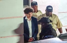 El fundador de FTX, Sam Bankman-Fried (izquierda), es llevado esposado por agentes de la Policía Real de Bahamas en Nassau, Bahamas.